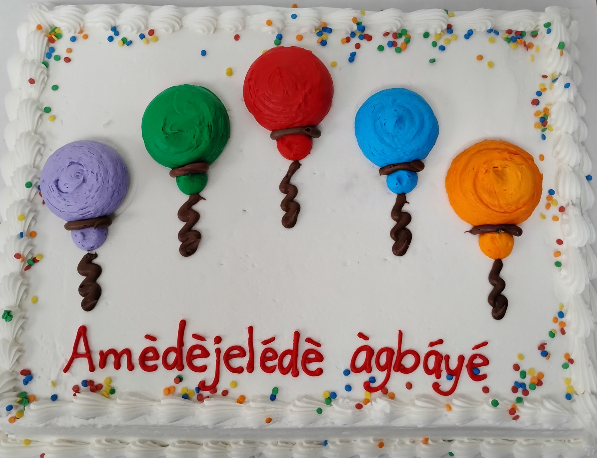 Fancy white sheetcake with Yoruba icing text